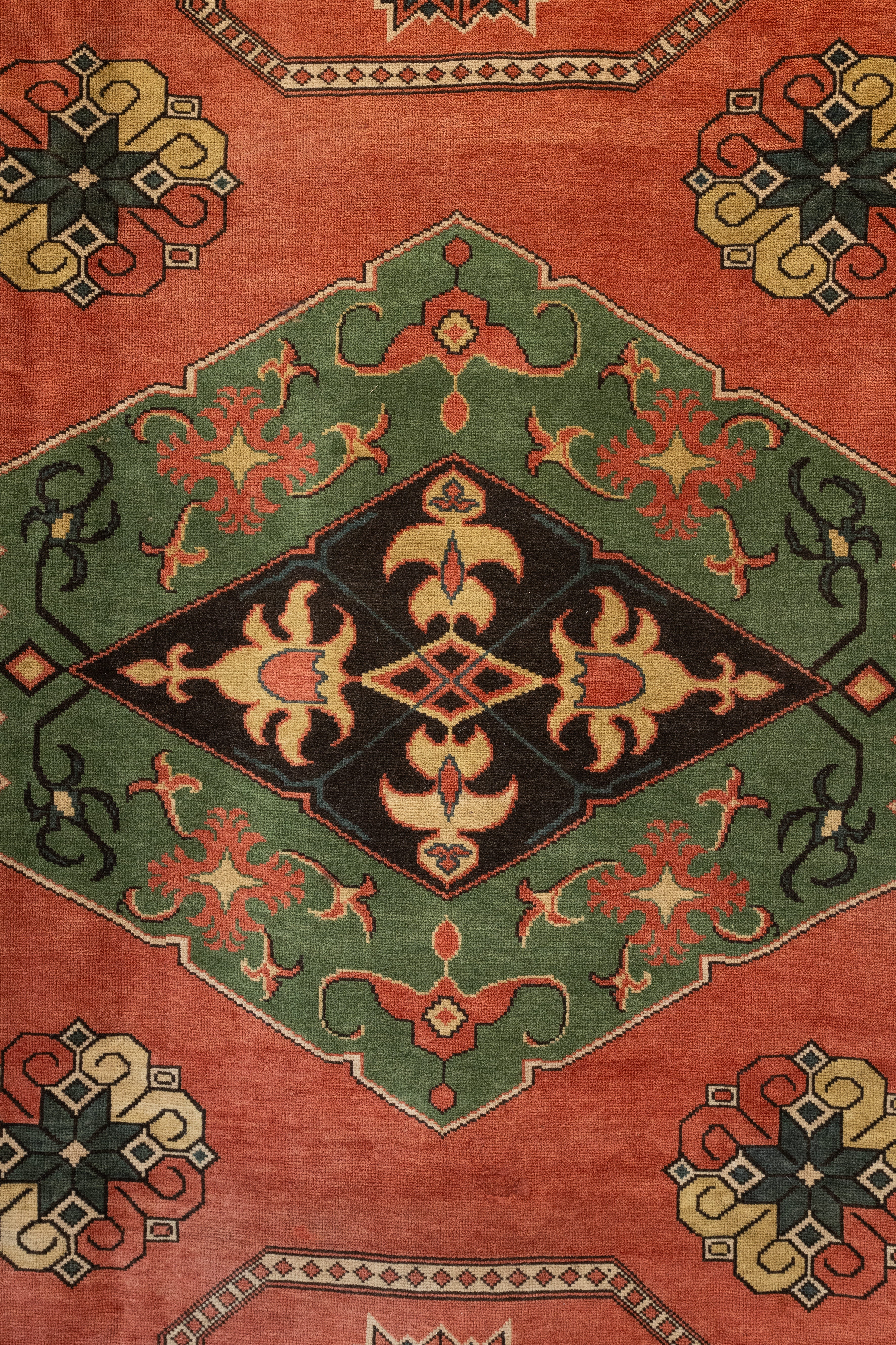 Close-up of a patterned rug with geometric designs on a red and green background.